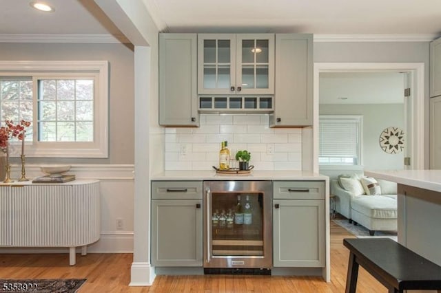 bar featuring ornamental molding, wine cooler, radiator heating unit, tasteful backsplash, and light wood finished floors