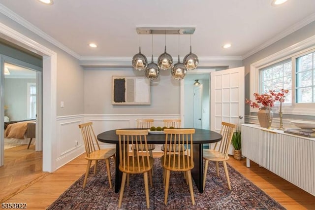 dining room featuring an inviting chandelier, radiator, a wainscoted wall, and light wood-style floors