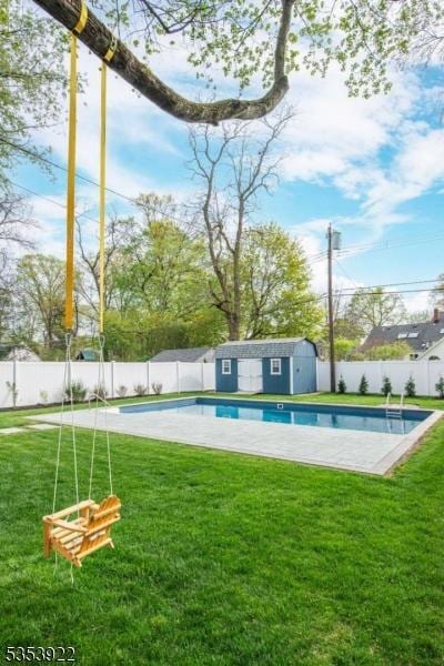 view of swimming pool with a fenced backyard, a fenced in pool, an outdoor structure, and a lawn