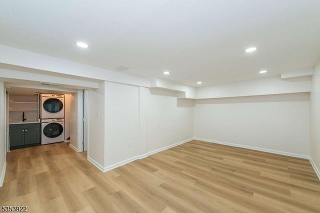 finished below grade area featuring stacked washing maching and dryer, baseboards, recessed lighting, and light wood-type flooring