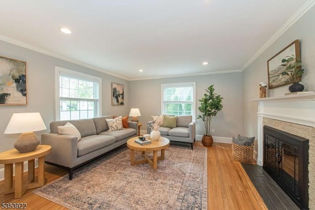 living room with ornamental molding, recessed lighting, a stone fireplace, and wood finished floors