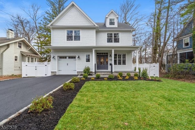 traditional-style house featuring covered porch, a front yard, a gate, fence, and aphalt driveway