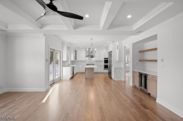 unfurnished living room with wine cooler, ornamental molding, ceiling fan with notable chandelier, and light wood-type flooring