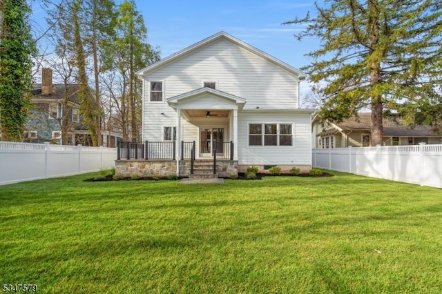 back of house with a lawn, a ceiling fan, and a fenced backyard