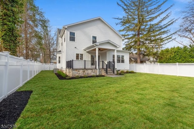 rear view of property with a yard, a ceiling fan, and a fenced backyard