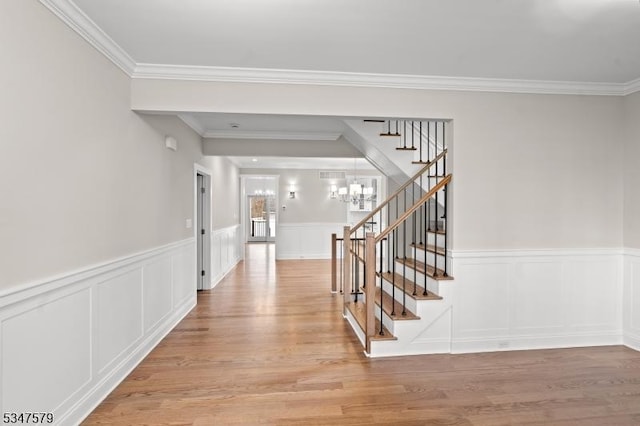 interior space with stairs, an inviting chandelier, ornamental molding, and light wood finished floors