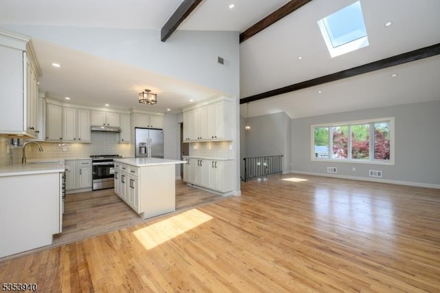 318 Sunnyside Ter, Bridgewater Twp, NJ 08807 - kitchen featuring appliances with stainless steel finishes, vaulted ceiling with skylight, open floor plan, tasteful backsplash, and a kitchen island