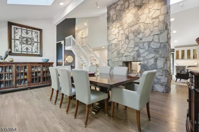dining space featuring stairway, a stone fireplace, wood finished floors, and recessed lighting