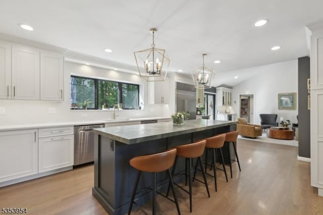 kitchen with appliances with stainless steel finishes, recessed lighting, a breakfast bar, light wood-type flooring, and a kitchen island
