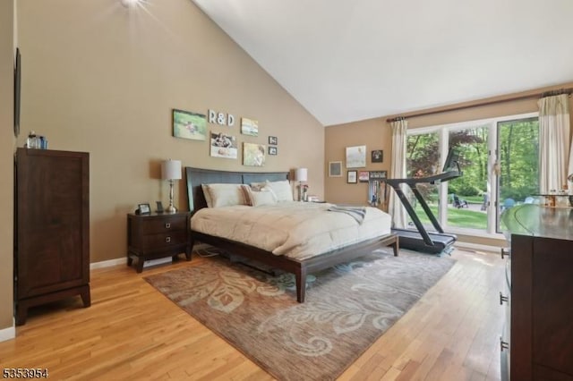 bedroom featuring light wood-type flooring, baseboards, and high vaulted ceiling