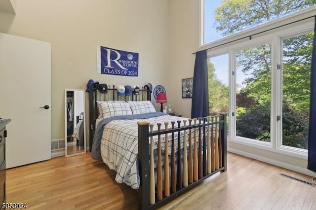 bedroom with light wood-style flooring and a high ceiling