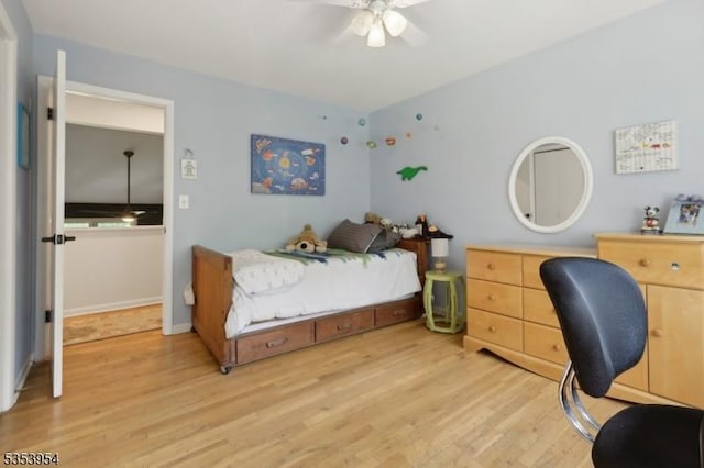 bedroom featuring light wood finished floors, a desk, a ceiling fan, and baseboards