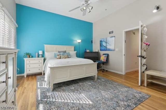 bedroom with light wood-type flooring, high vaulted ceiling, ceiling fan, and baseboards