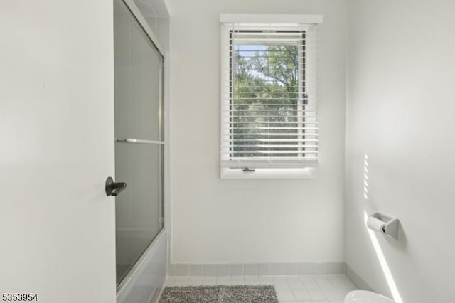 bathroom with baseboards and shower / bath combination with glass door