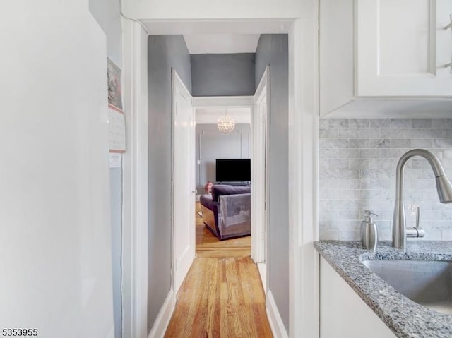 hall with a sink, light wood-style flooring, and a chandelier