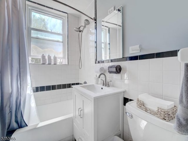 bathroom with toilet, tile walls, shower / bathtub combination with curtain, and vanity