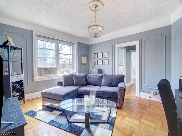 living room with baseboards, cooling unit, a textured ceiling, and a notable chandelier