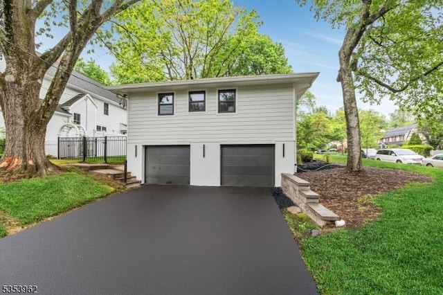 view of side of home featuring asphalt driveway, an attached garage, fence, and stucco siding