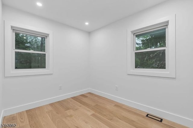 empty room with baseboards, light wood finished floors, and recessed lighting