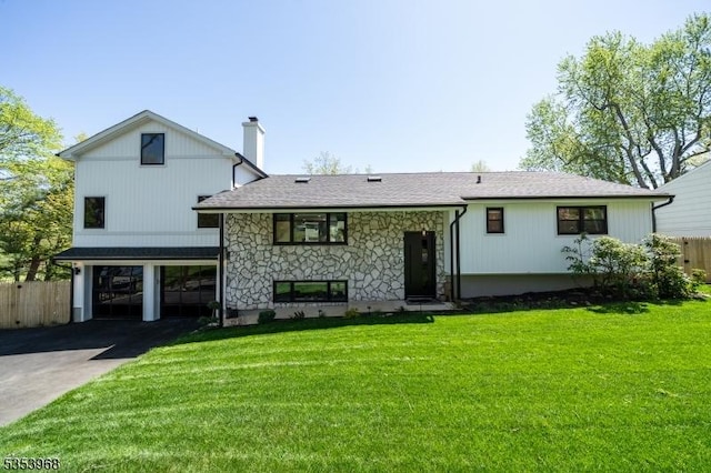 back of property with fence, an attached garage, a chimney, and driveway