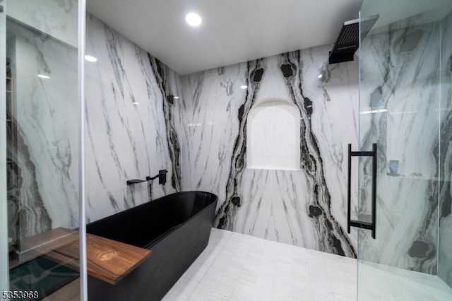bathroom featuring a marble finish shower and a freestanding bath