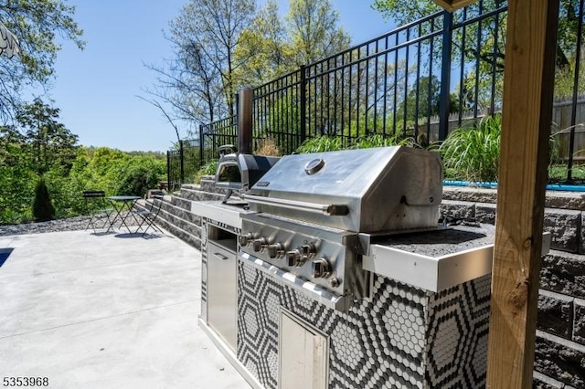 view of patio with exterior kitchen and a grill