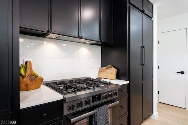 kitchen with dark cabinets, light countertops, light wood-style flooring, and gas stove