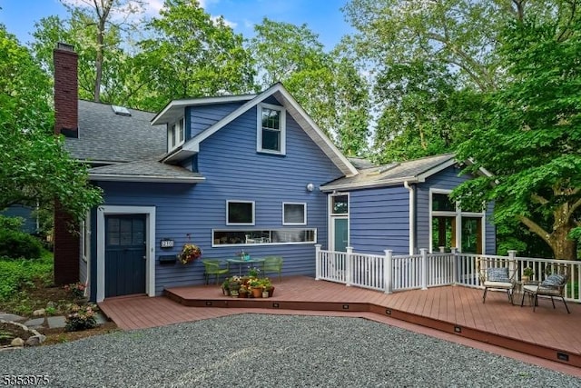 back of property featuring a wooden deck, a shingled roof, and a chimney
