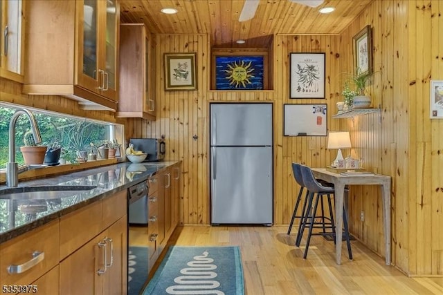 kitchen with freestanding refrigerator, light wood-style floors, a sink, wood ceiling, and wooden walls