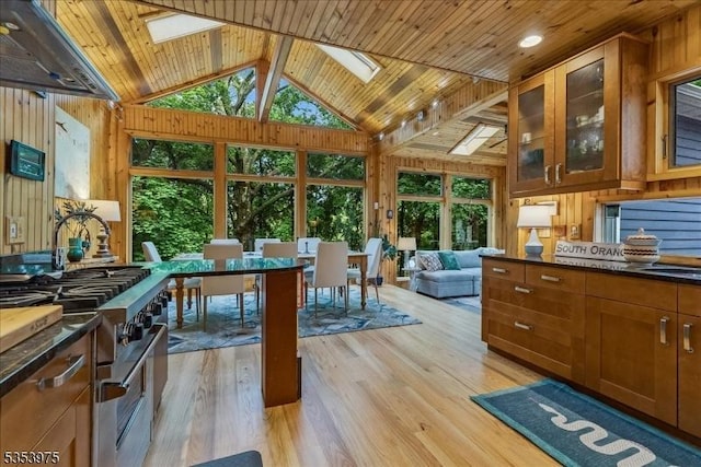 kitchen featuring stainless steel range, a skylight, wooden walls, dark countertops, and wood ceiling