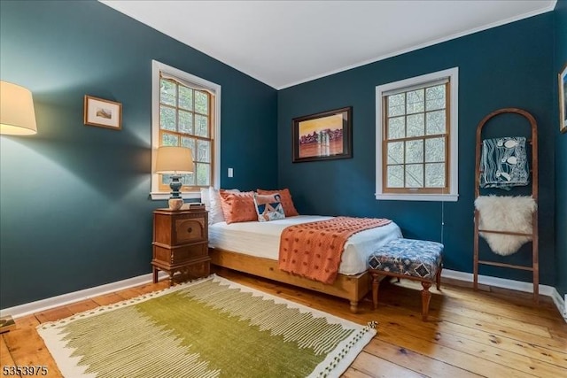 bedroom with ornamental molding, hardwood / wood-style flooring, and baseboards