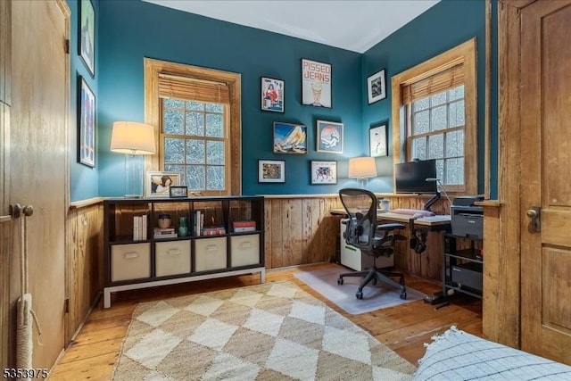 office area with a wainscoted wall, hardwood / wood-style flooring, and wooden walls