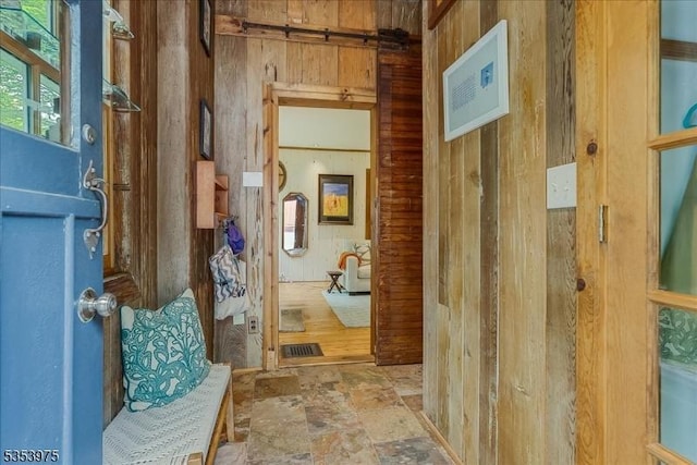 hallway featuring wood walls and stone finish flooring