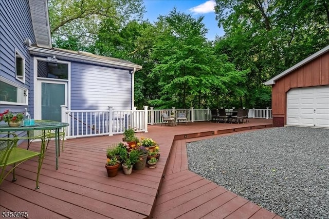 wooden terrace with outdoor dining space, a garage, and view of wooded area