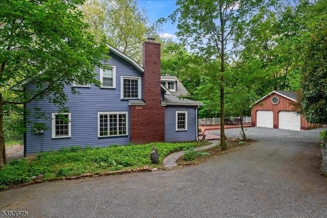 view of home's exterior featuring an outdoor structure, a detached garage, and a chimney