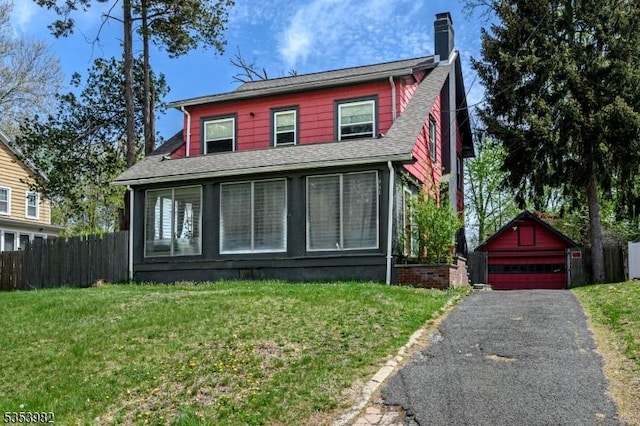 view of front of property featuring fence, a front lawn, a garage, a chimney, and an outdoor structure