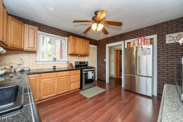 kitchen with brick wall, ceiling fan, dark wood-style floors, backsplash, and stainless steel appliances