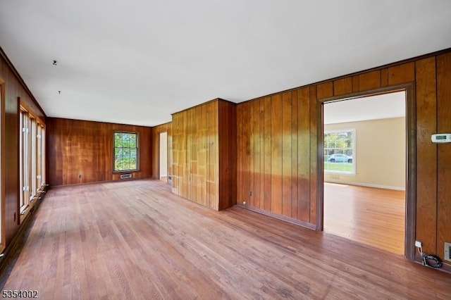 unfurnished living room with wood walls, plenty of natural light, and wood finished floors