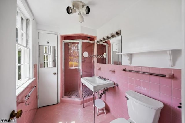full bath featuring toilet, tile patterned floors, tile walls, and a stall shower