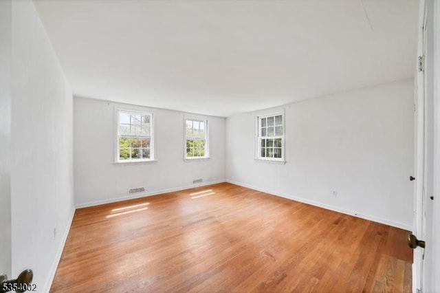 spare room featuring baseboards, light wood finished floors, and visible vents