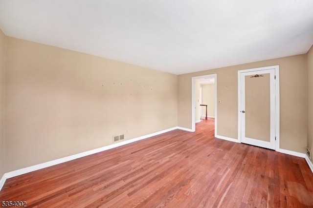 unfurnished room featuring baseboards, wood finished floors, and visible vents
