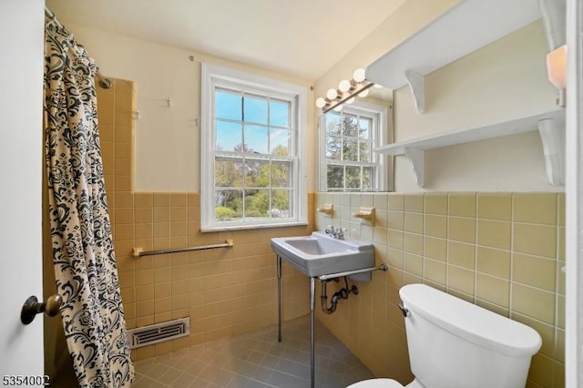 full bath featuring visible vents, a shower with curtain, toilet, and tile walls