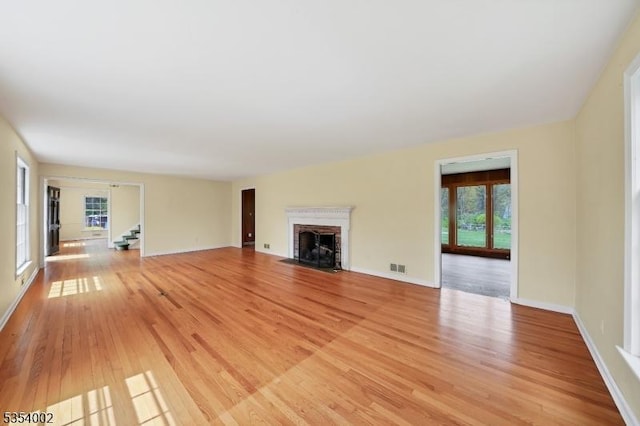 unfurnished living room with light wood-type flooring, stairs, and a wealth of natural light