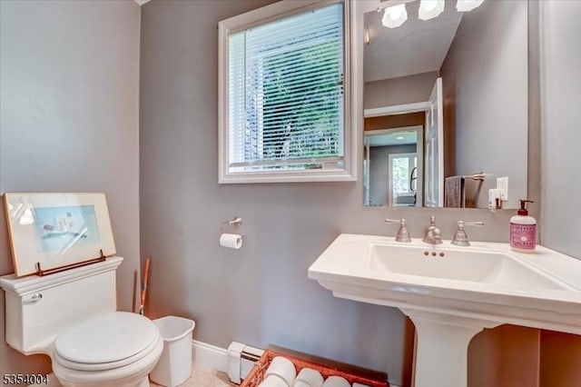 half bathroom featuring toilet, baseboards, a sink, and a baseboard radiator
