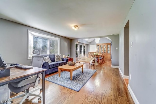 living area with baseboards, arched walkways, and wood finished floors