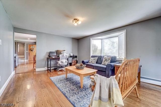 living area with baseboards, a baseboard heating unit, and wood finished floors