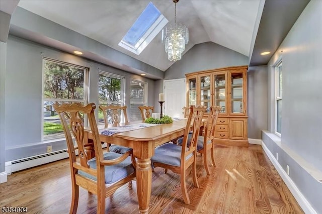 dining room featuring a notable chandelier, baseboard heating, vaulted ceiling with skylight, baseboards, and light wood-type flooring