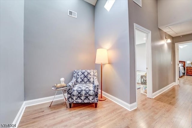 sitting room featuring baseboards, attic access, wood finished floors, and visible vents