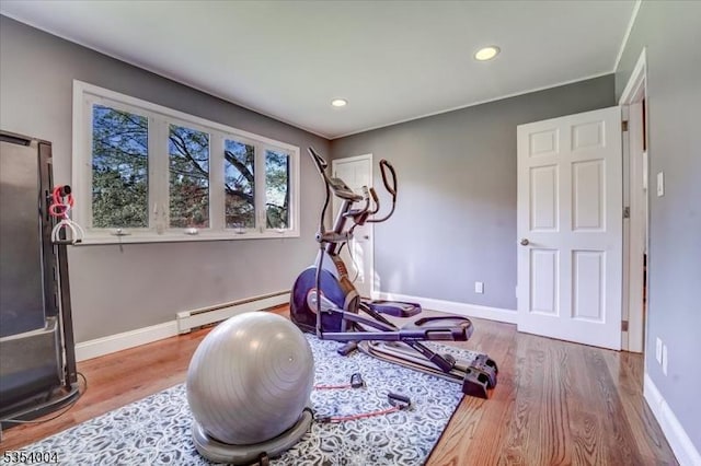 exercise area featuring baseboards, a baseboard heating unit, recessed lighting, and wood finished floors