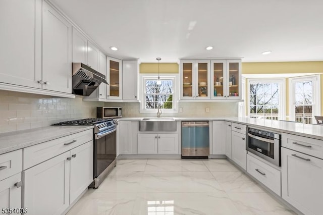 kitchen with a sink, marble finish floor, stainless steel appliances, recessed lighting, and under cabinet range hood